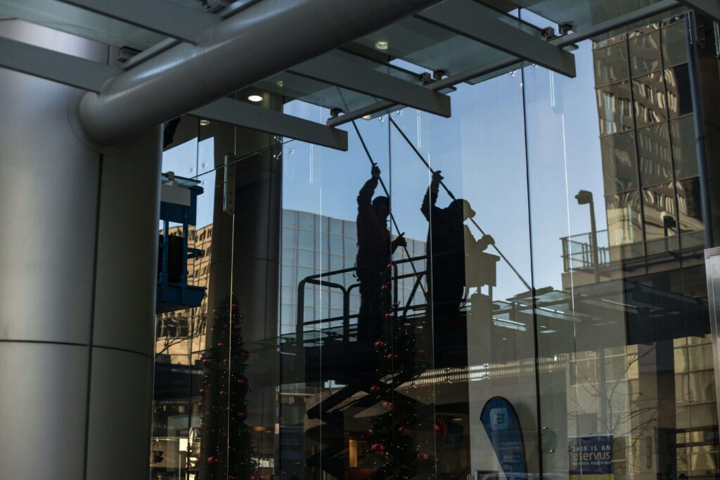A person on a lift dusting the exterior of a glass building