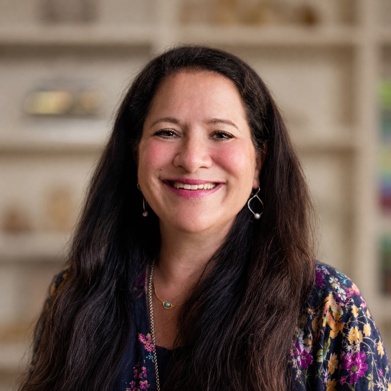 Dru Headshot - a woman with long brown hair smiling at the camera